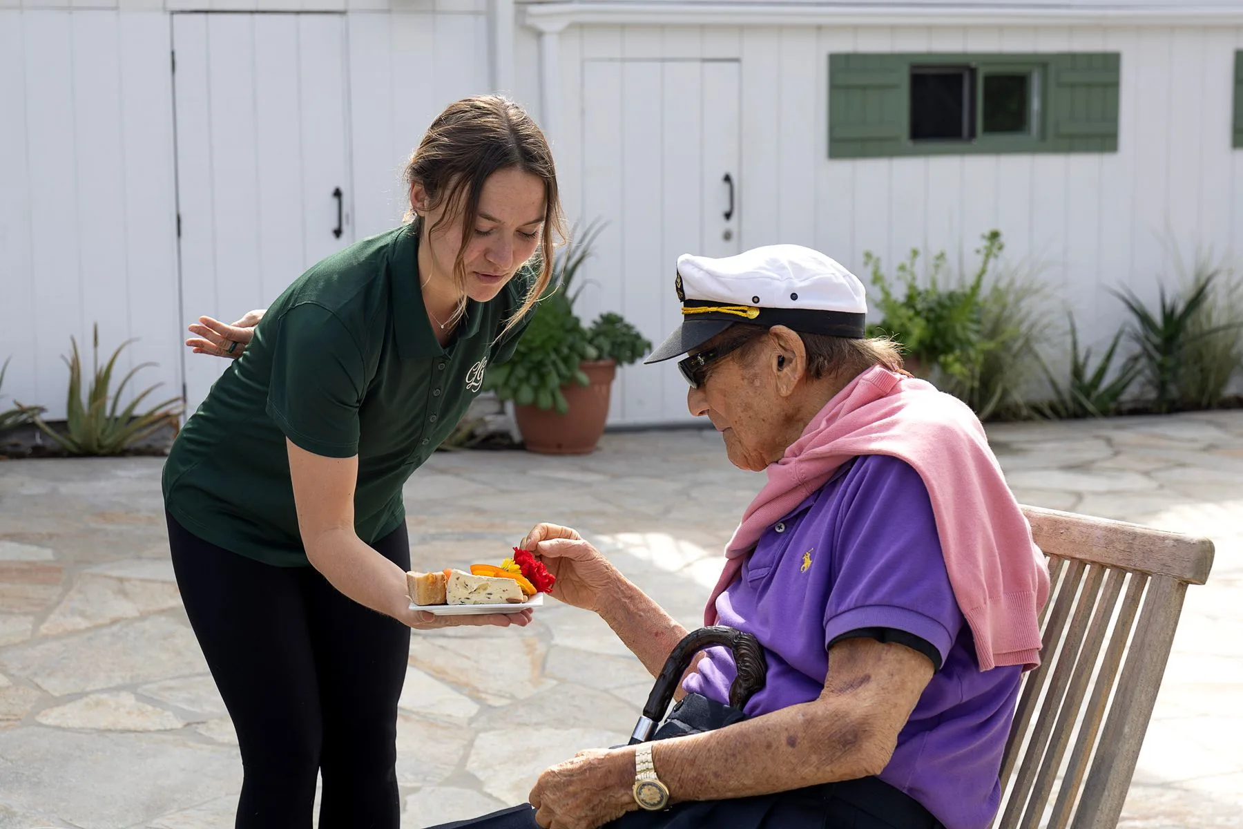 Casa La Granada caregiver serving a resident in the courtyard